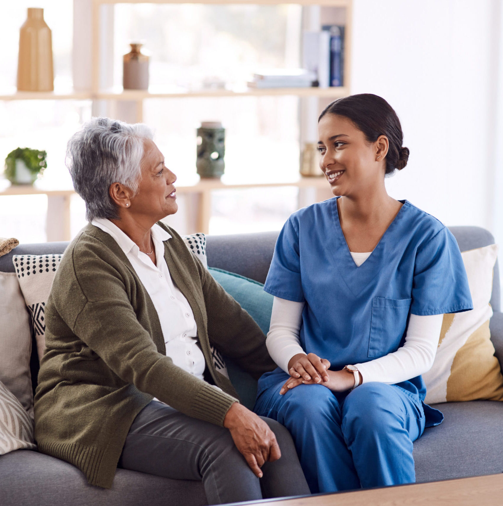 Healthcare, retirement and a nurse talking to an old woman on a sofa in the living room of a nursing home. Medical, trust and care with a female medicine professional chatting to a senior resident.